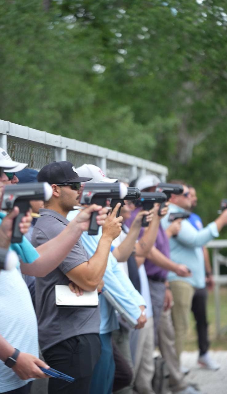 A line of college scouts tracking an A3 pitcher with radar guns
